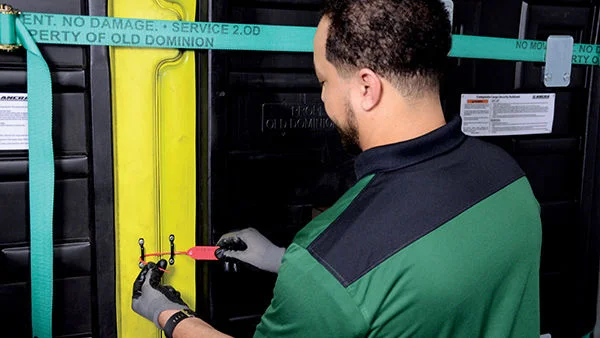 ODFL employee securing a freight trailer with a tamper-resistant seal for shipment protection.